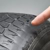 hand pointing towards car's tyre