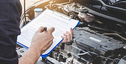 Car owner ticking items from his checklist after inspecting the engine