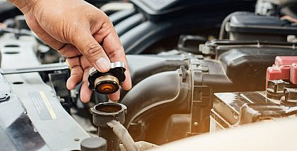 A man checking car radiator by opening the cap