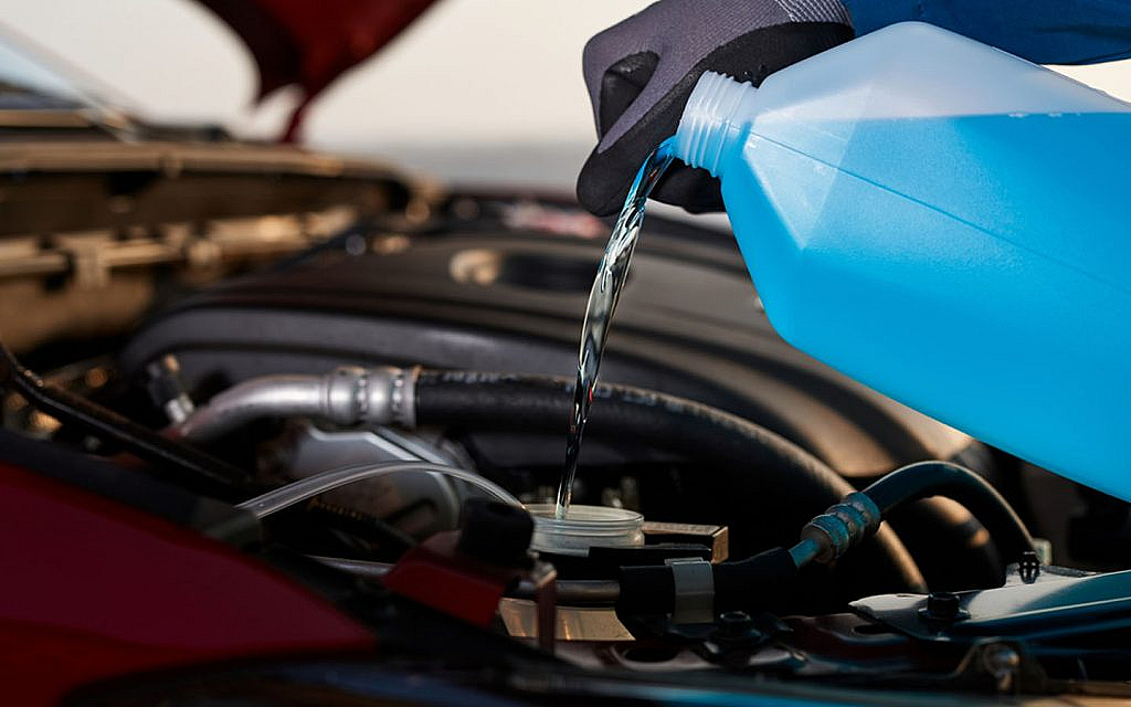 A person is adding coolant into the radiator