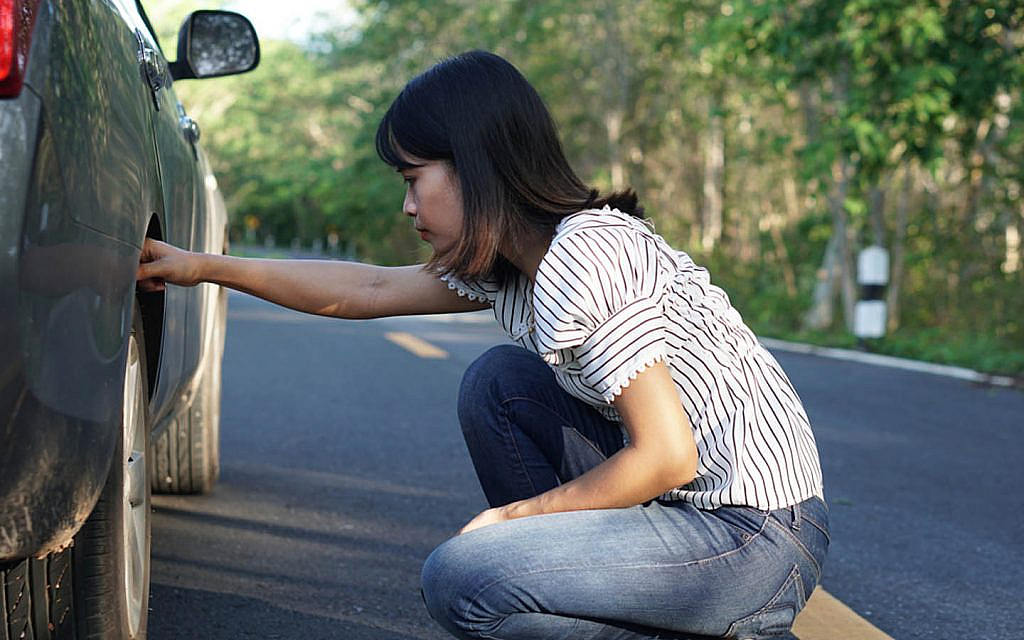 Woman checking her car’s tires