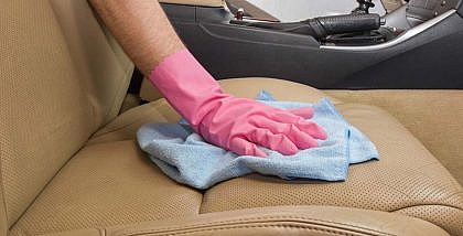 A man cleaning leather car seats with a cloth