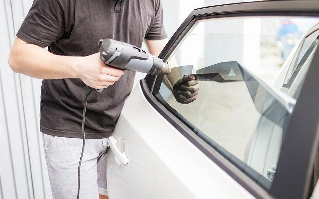 Man removing car tint with a heat gun