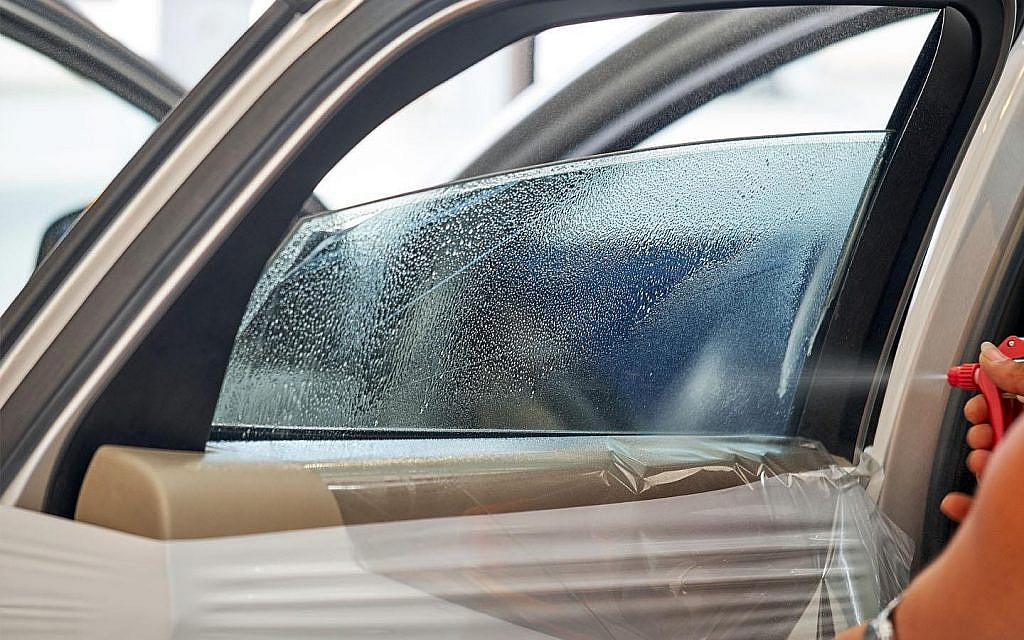 Woman spraying soap water solution on a car tint