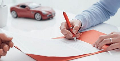 Man signing a document after selling a car with a loan