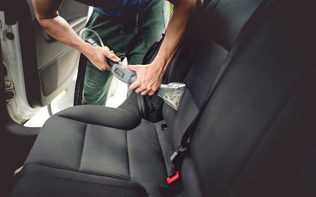 A man is cleaning the back seats of the car