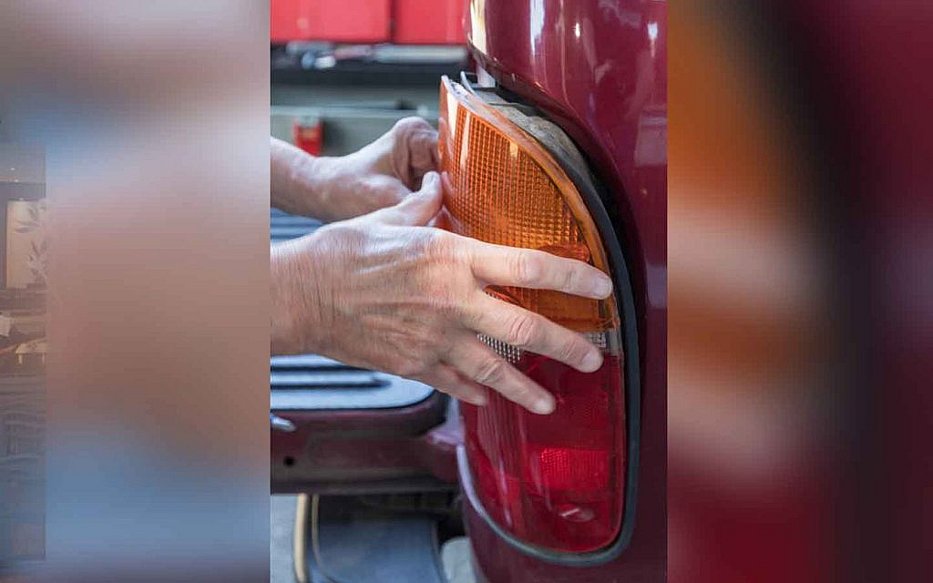 A man replacing a tail light assembly 