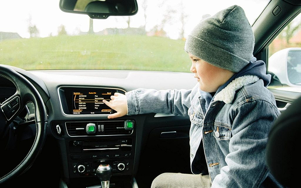 Boy sitting alone in the car, playing with the car sound system