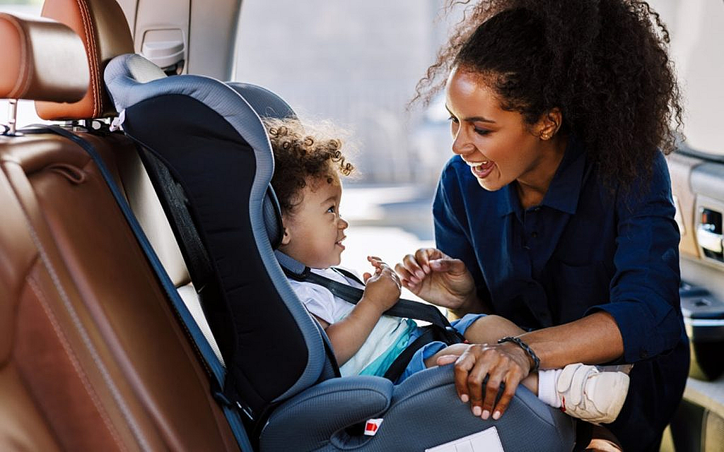 Mother placing her child in a child car seat