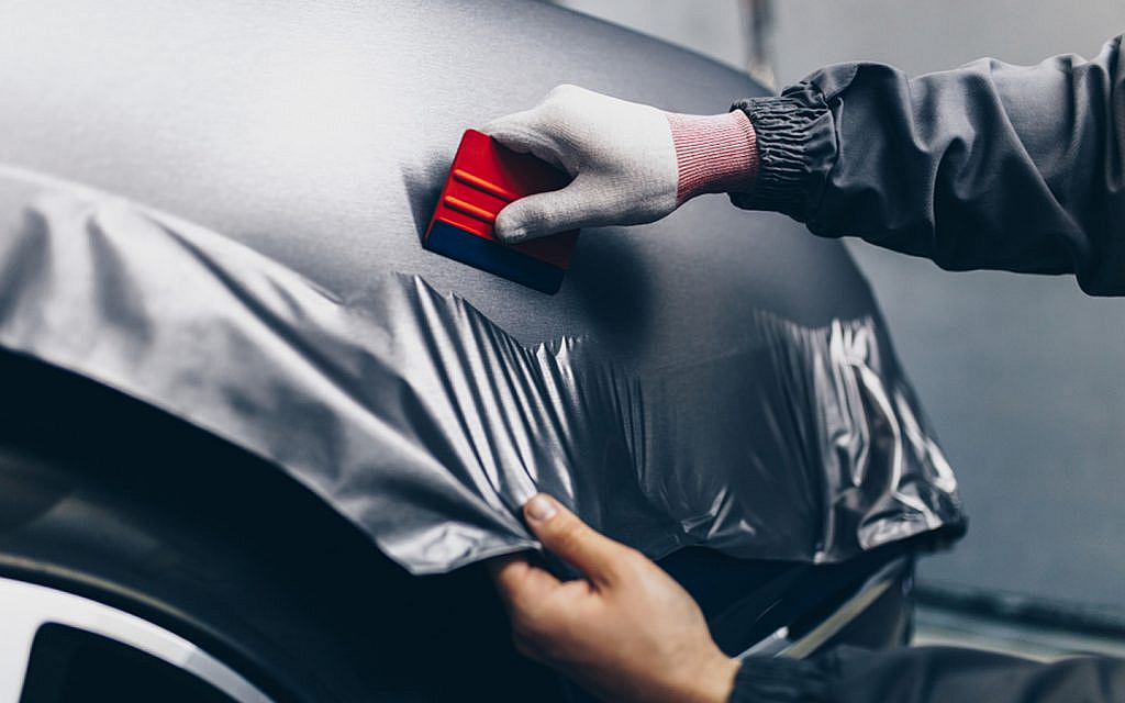 Car wrapping specialist applying vinyl foil on car