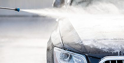 A car under the water jet during the steam washing process