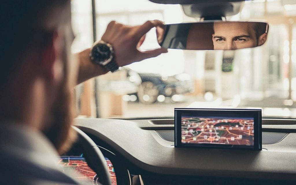 Man setting rear-view mirror before starting his car