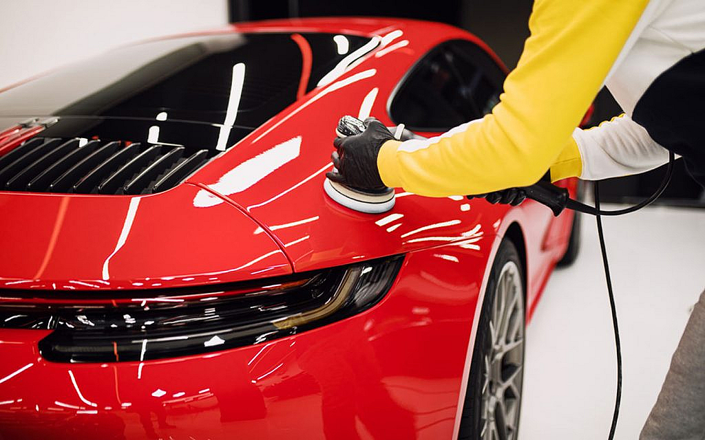 A worker polishing a car with an orbital polisher