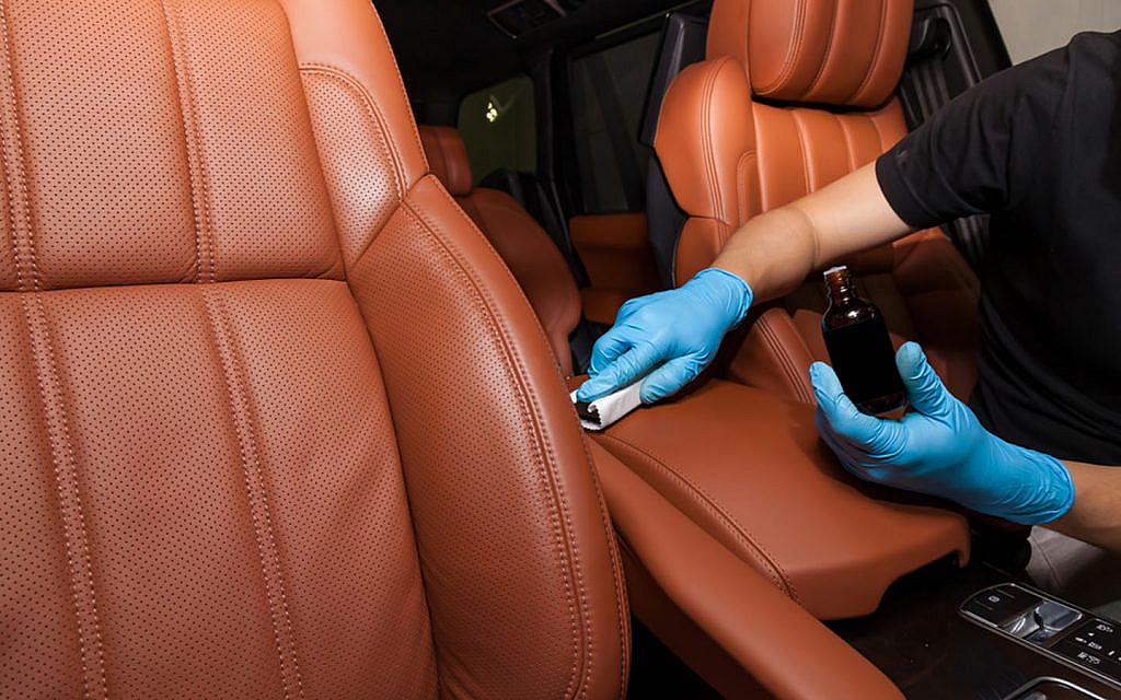 Person cleaning car seat with car upholstery shampooer