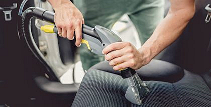 Man cleaning car upholstery with a vacuum cleaner