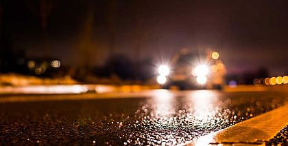 A car’s headlight is on while travelling on the road