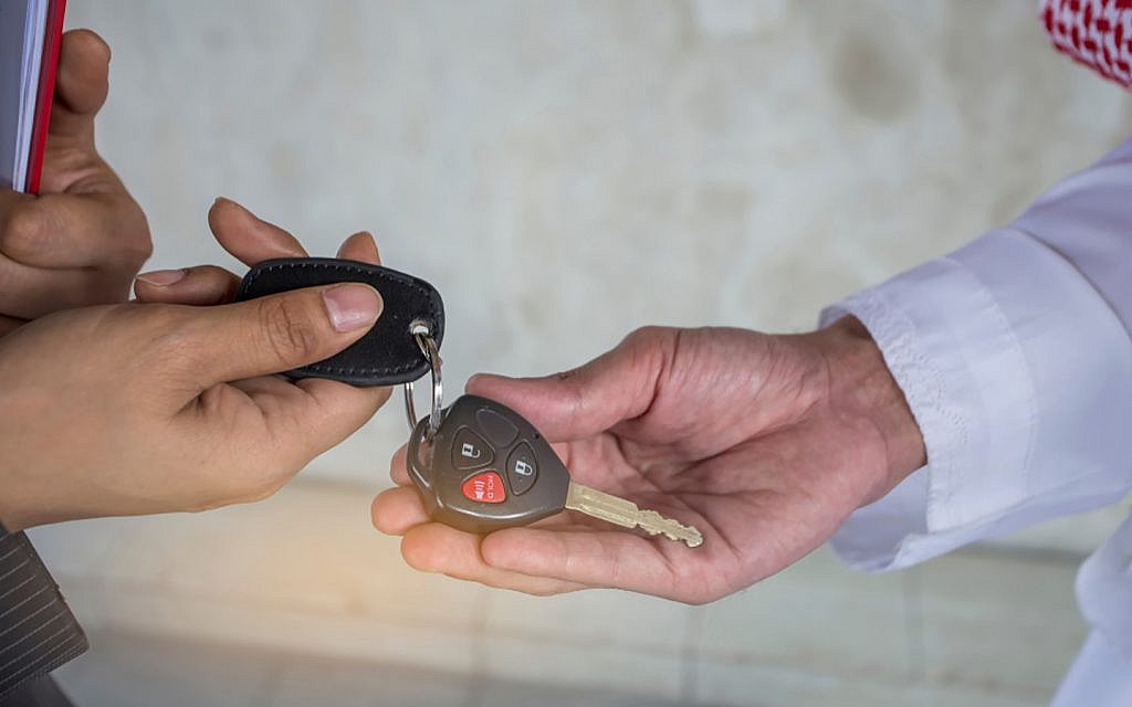 A salesman handing over the car’s key and remote to the buyer
