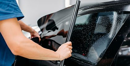 رجل يقوم بتظليل زجاج سيارة