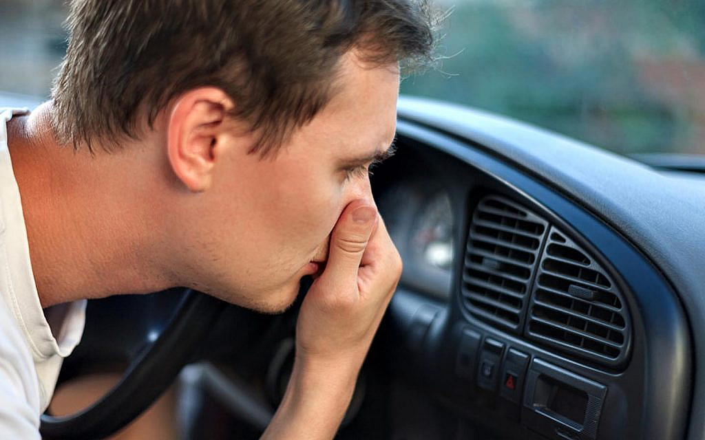 A man smelling a bad smell in the car