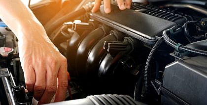 A person cleaning car engine with Sea Foam