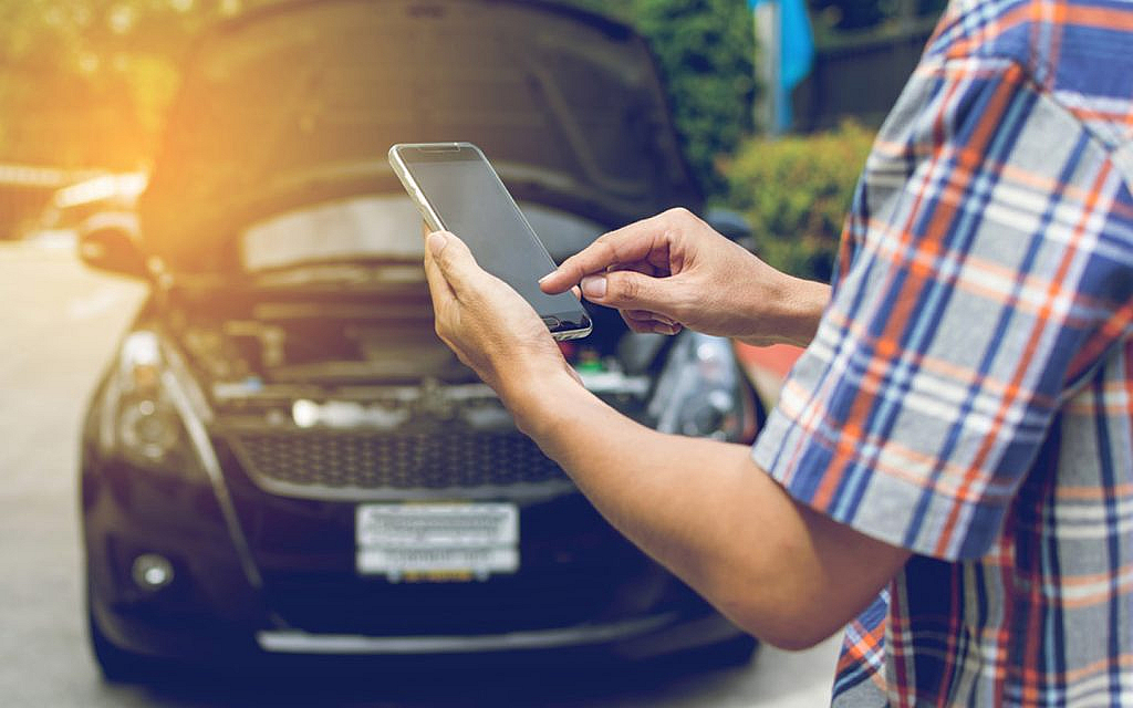A man using phone to with a broken down car