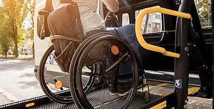 Man in a wheelchair on a ramp getting inside a wheelchair accessible transportation vehicle