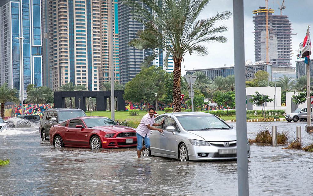 People pushing their cars in a flooded road 