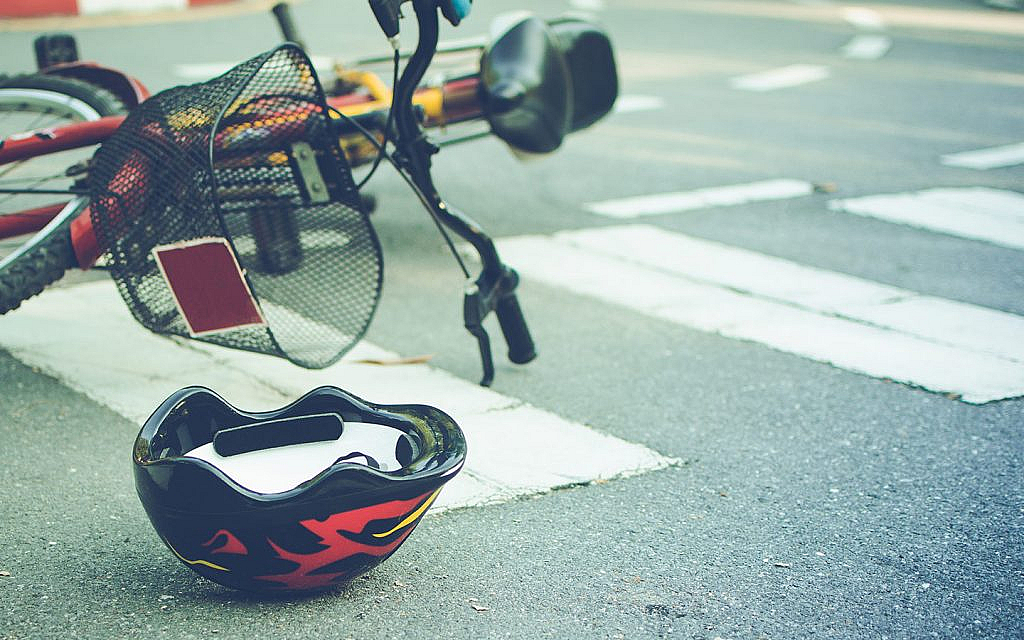 Helmet and bike lying on the road on a pedestrian crossing