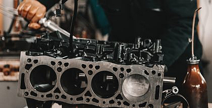 Auto mechanic adjusting cracked cylinder head on the engine block with a wrench