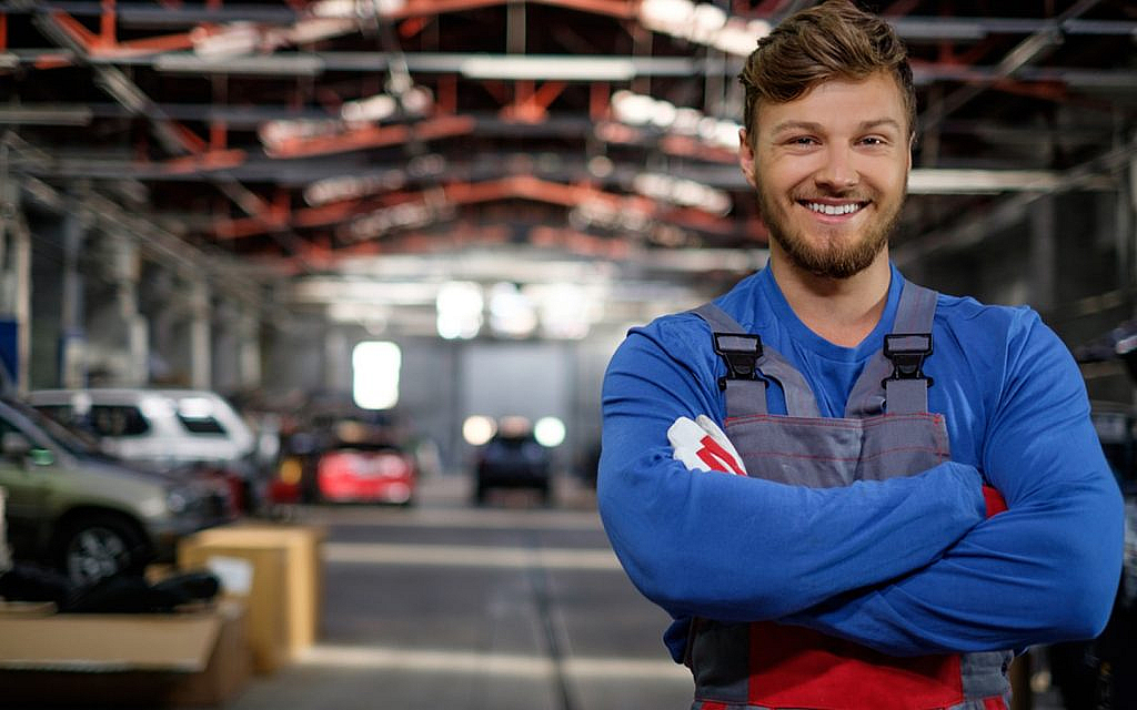 A car mechanic is smiling after completing his work
