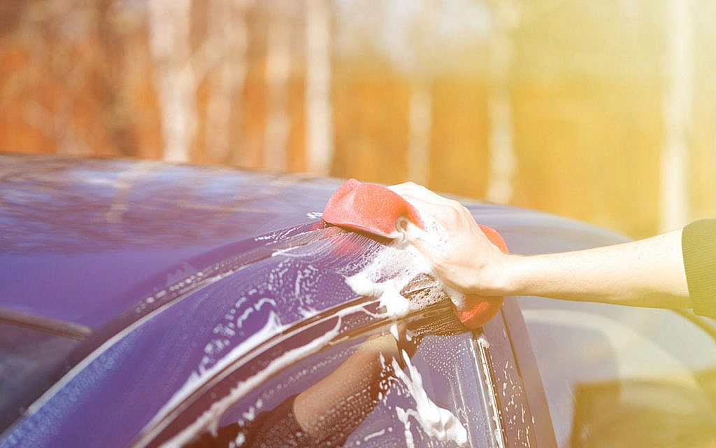 Woman cleaning car with car wash shampoo