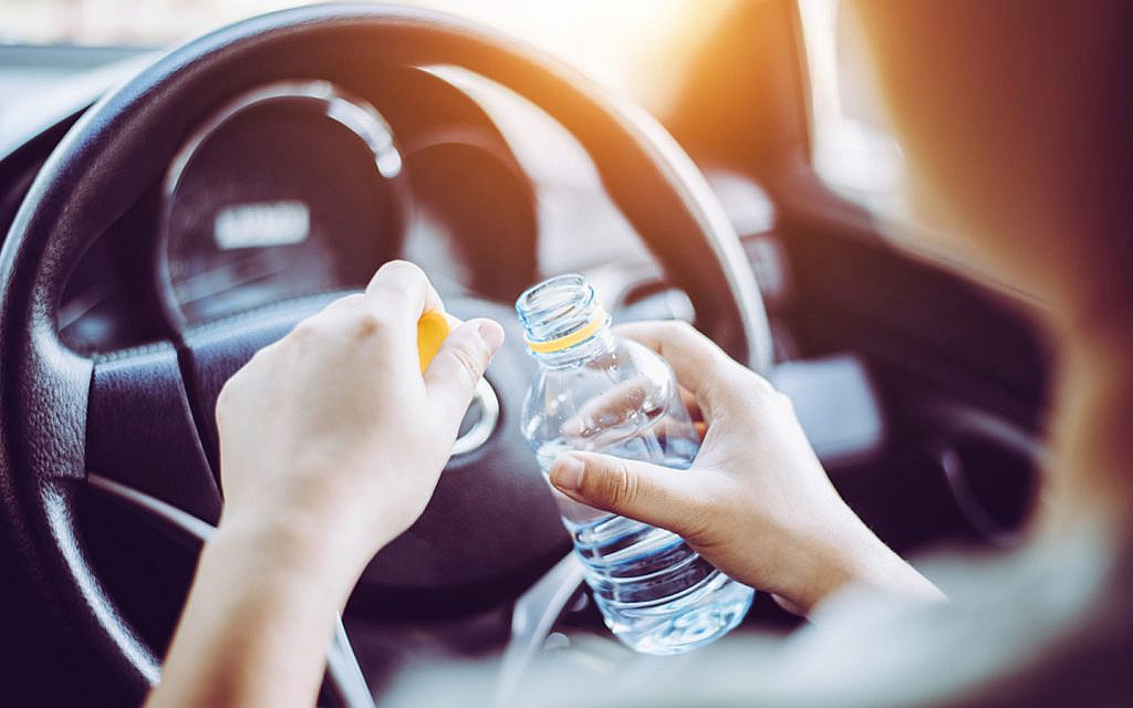 A woman drinking water while driving during pregnancy