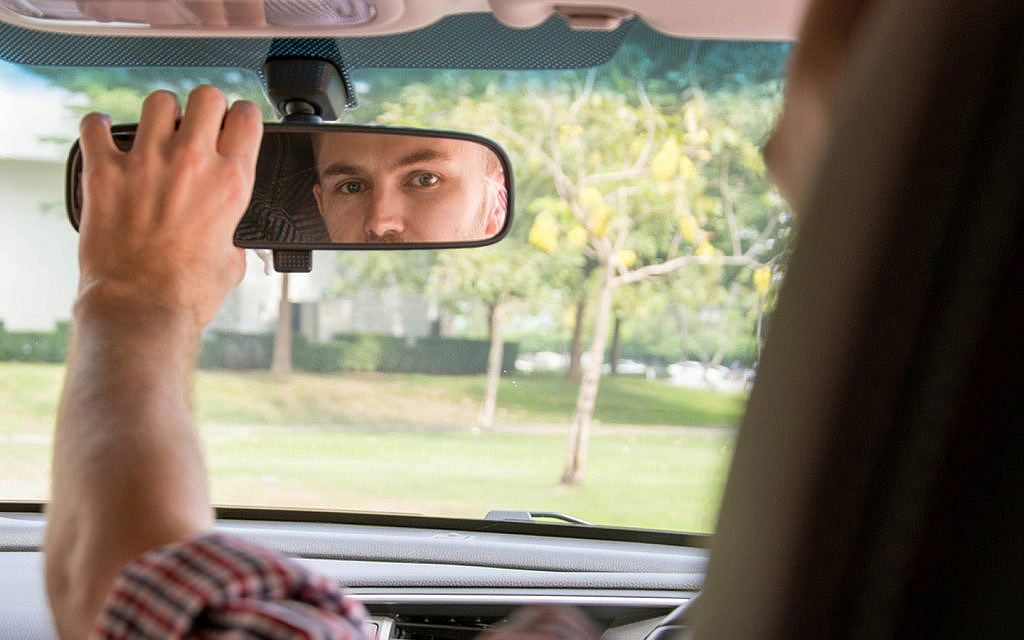 driver adjusting the car's rear mirror