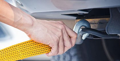 Using recovery straps. Man fixing recovery strap beneath the pulling vehicle