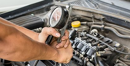A mechanic is checking if there is low engine compression