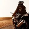 Motorcyclist riding on an open road at sunset.