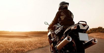Motorcyclist riding on an open road at sunset.