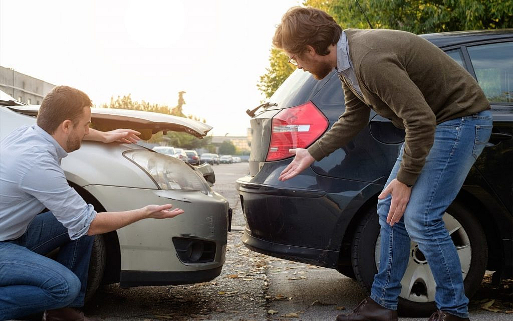 شخصين بجانب سيارتين بعد التصادم