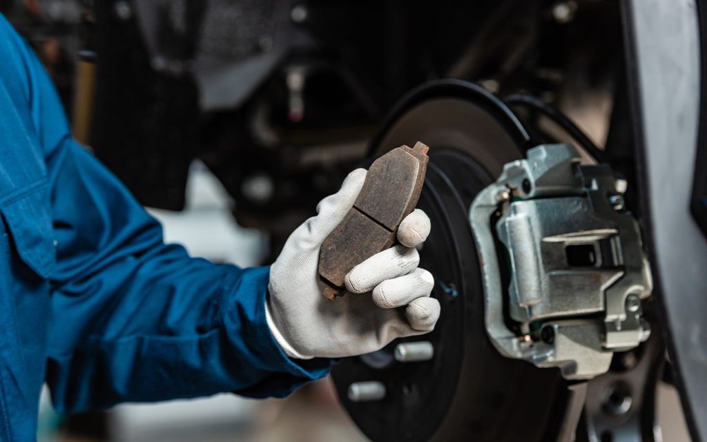 worn out car brake pads shown by mechanic