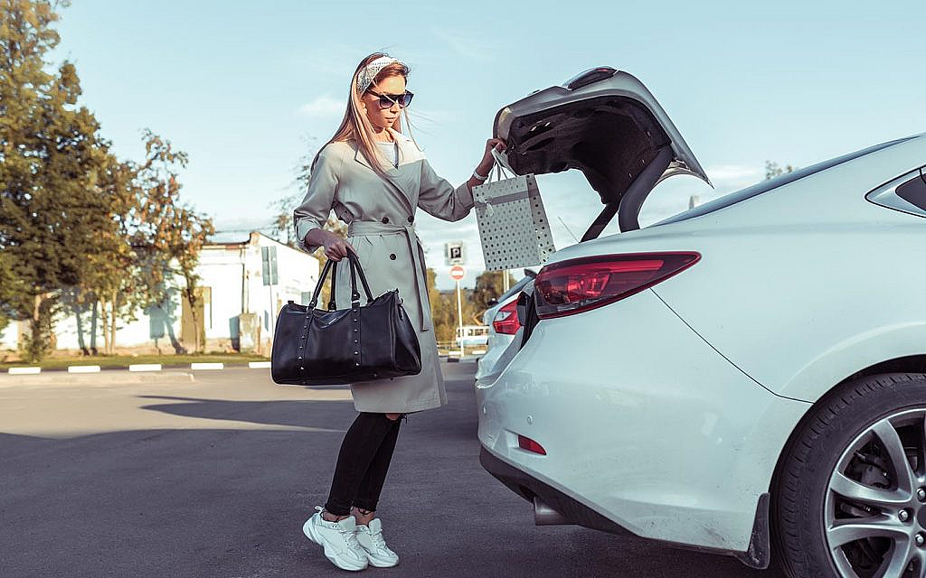 امرأة تضع أمتعتها في صندوق سيارة بيضاء اللون