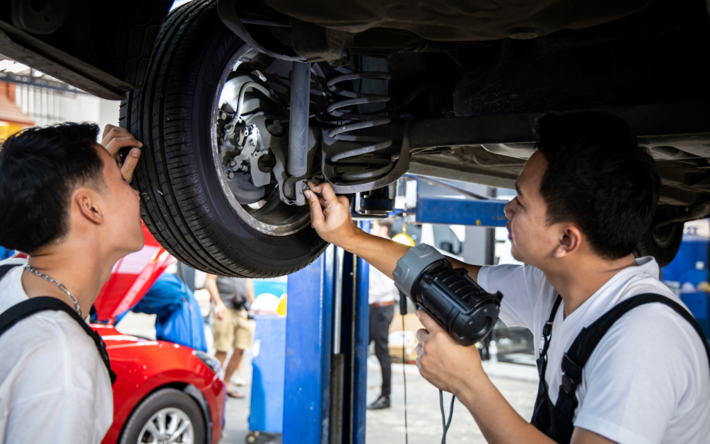 mechanics looking at raised suspension of a car