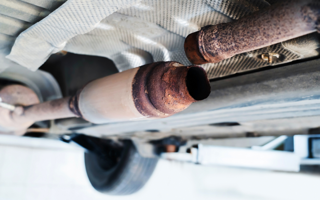 closeup of a rusted car muffler disconneted from the exhaust