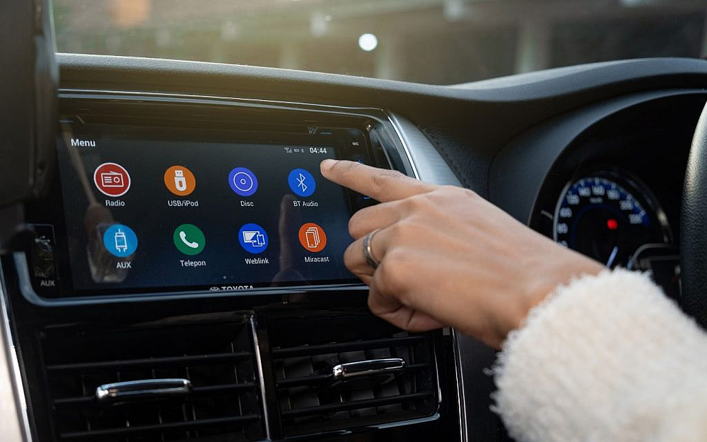 سائقة تضغط على أداة البلوتوث على شاشة سيارة