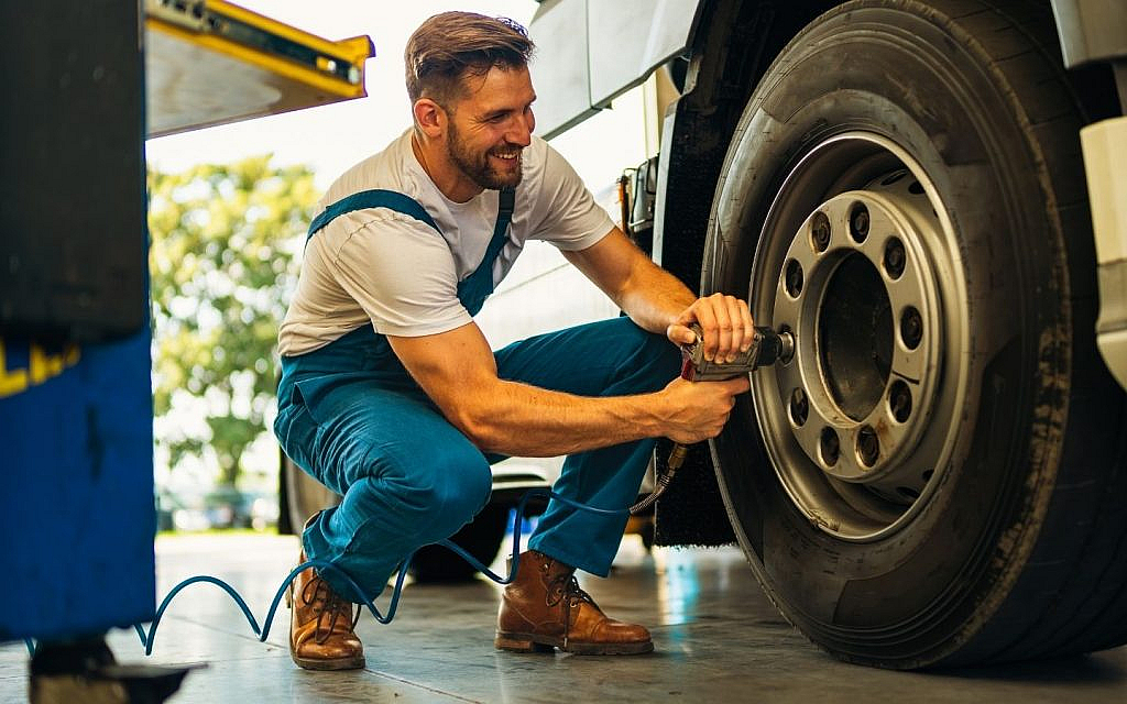 A mechanic in a white shirt replacing tyre
