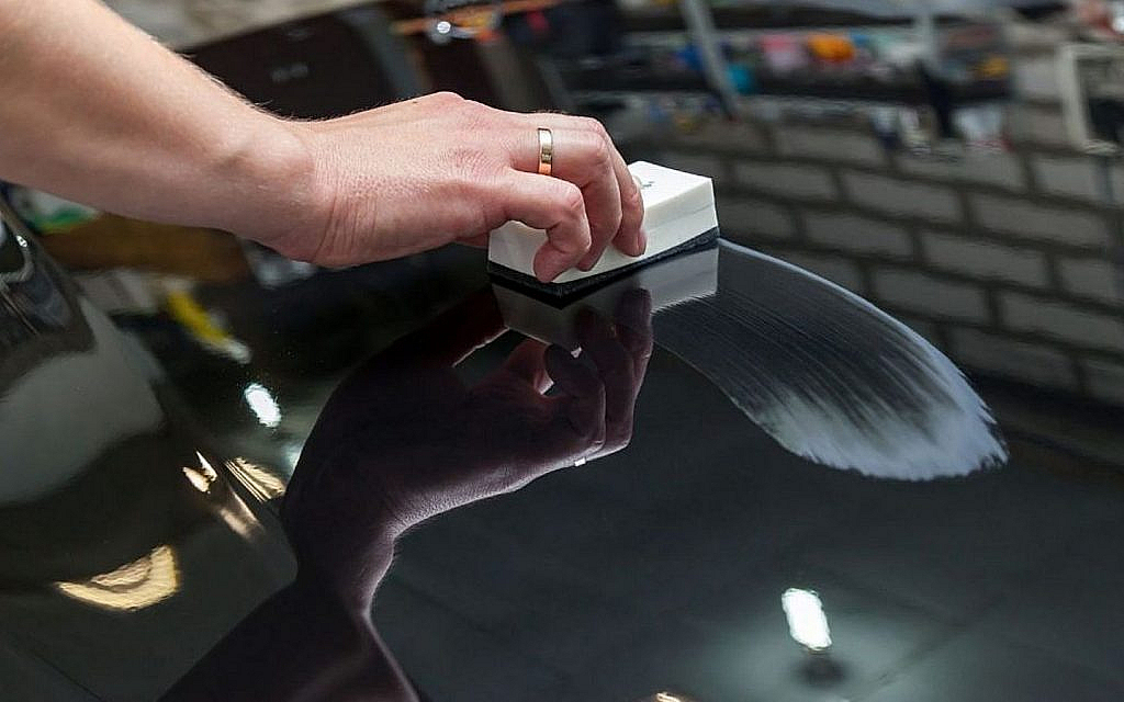 Wax is applied on a black car