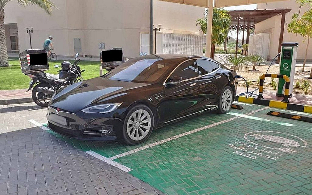 A black Tesla parked under a public charging station