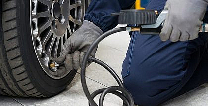 عامل يقوم بفحص ضغط الإطارات بجهاز
