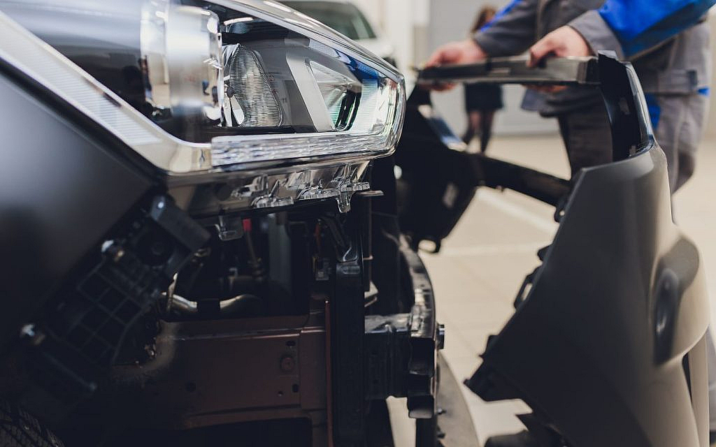 Car repair in progress, showing headlight and bumper removal.