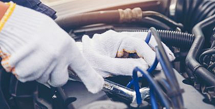Hands with gloves repairing engine of a car