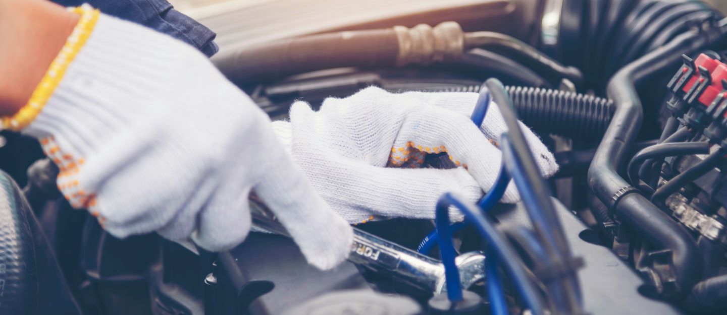 Hands with gloves repairing engine of a car